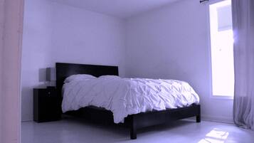 Una camera da letto con un letto, un comodino e una finestra con tende.