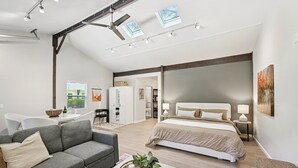 A spacious room with a large bed, a sofa, a dining table, and a kitchen area. - Pet Friendly Studio with Private Fenced Yard (Jacksonville)