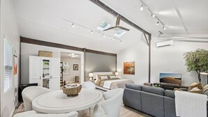 A modern living room with a round dining table, grey sofa, and a bed with a view. - Pet Friendly Studio with Private Fenced Yard (Jacksonville)