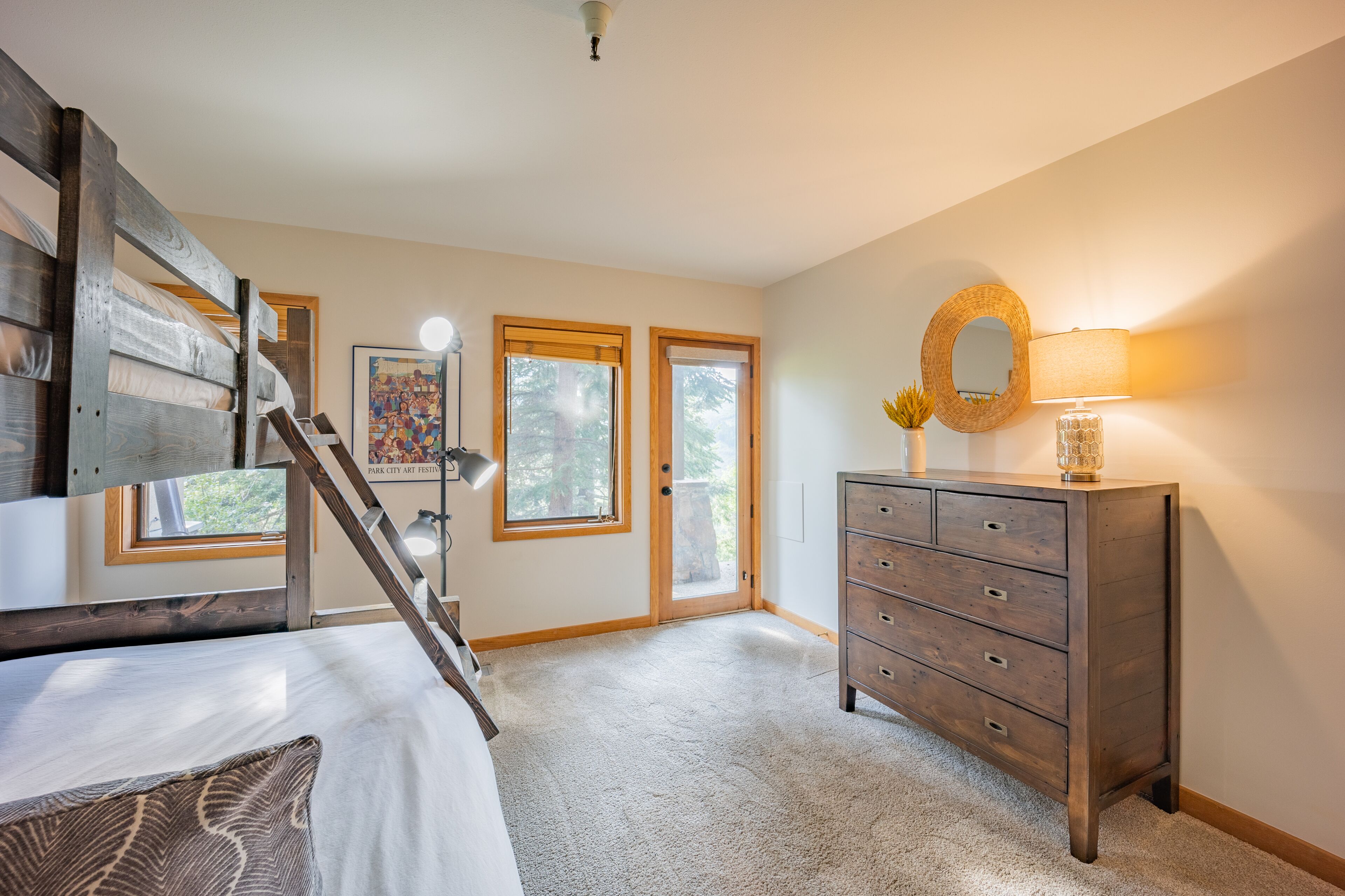 A bedroom with a bed, dresser, and a staircase.