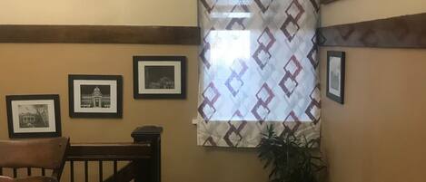 A staircase with a wooden railing, a patterned window, and framed pictures on the wall.