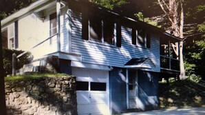 A two-story house with a stone wall foundation, a garage, and a porch.