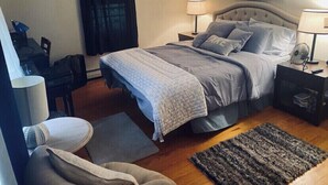 A bedroom with a bed, bedside tables, a desk, a chair, and a rug.
