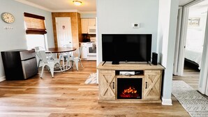 Ein gemütliches Wohnzimmer mit Fernseher, Kamin und Essbereich mit Stühlen und Tisch.