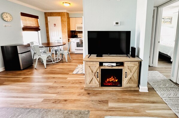 A cozy living room with a TV, a fireplace, and a dining area with chairs and a table.