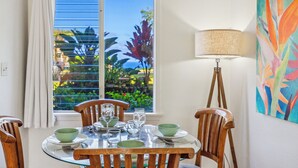 Un comedor con una mesa redonda, sillas y ventana con vista a la vegetación.
