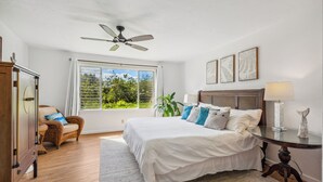 Un dormitorio con cama, una silla, una mesa y un ventilador de techo.