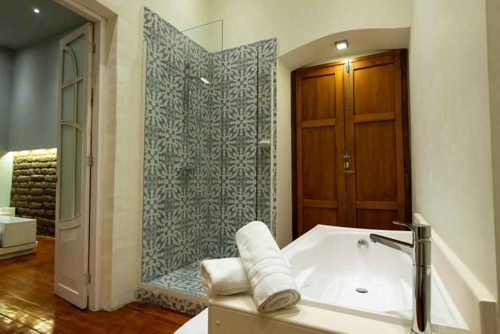 A bathroom with a shower, a bathtub, and a wooden door.