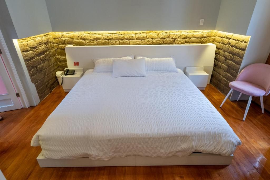 Un dormitorio con una cama grande, una mesita de noche con lámpara y una silla.