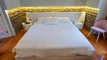 Un dormitorio con una cama grande, una mesita de noche con lámpara y una silla.