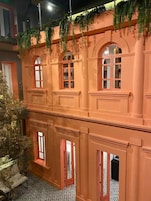 En model af en bygning med flere vinduer og altaner, i klassisk arkitektonisk stil med buede vinduer og dekorative gerichter.