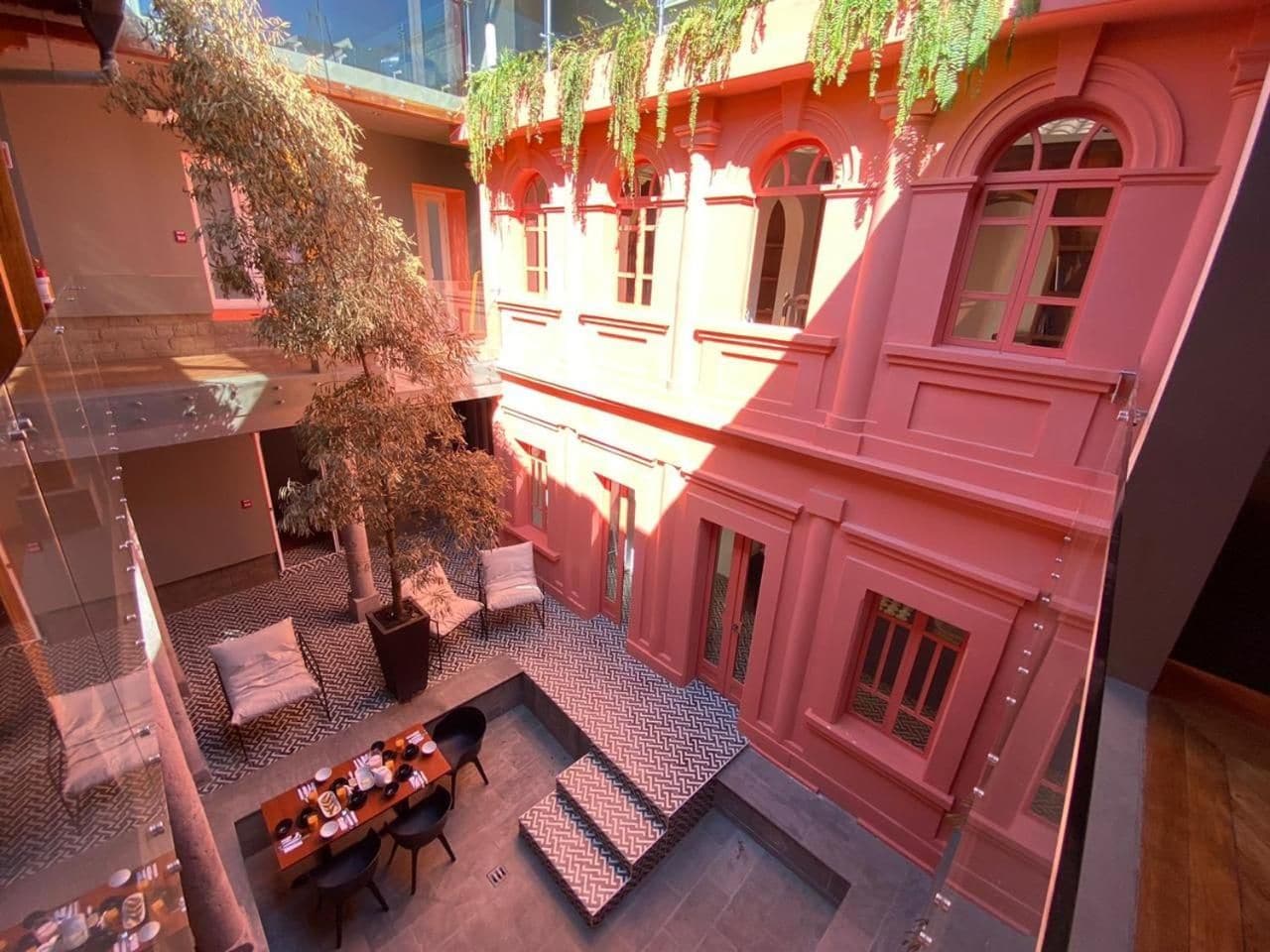 A courtyard with a dining area, a staircase, and a building with arched windows.