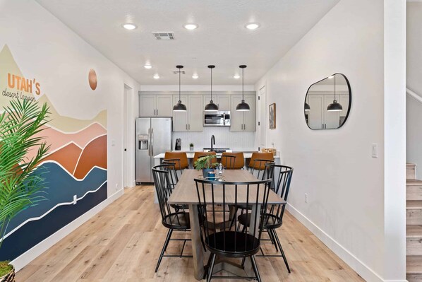 A modern kitchen with white cabinets, a central island, and pendant lighting. - Desert Lagoon #74 by RedAwning (St. George)