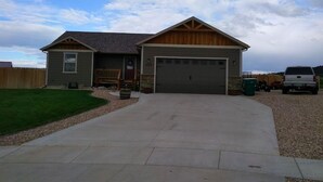 Une maison à deux étages avec un garage à l’avant, une véranda et une pelouse bien entretenue.