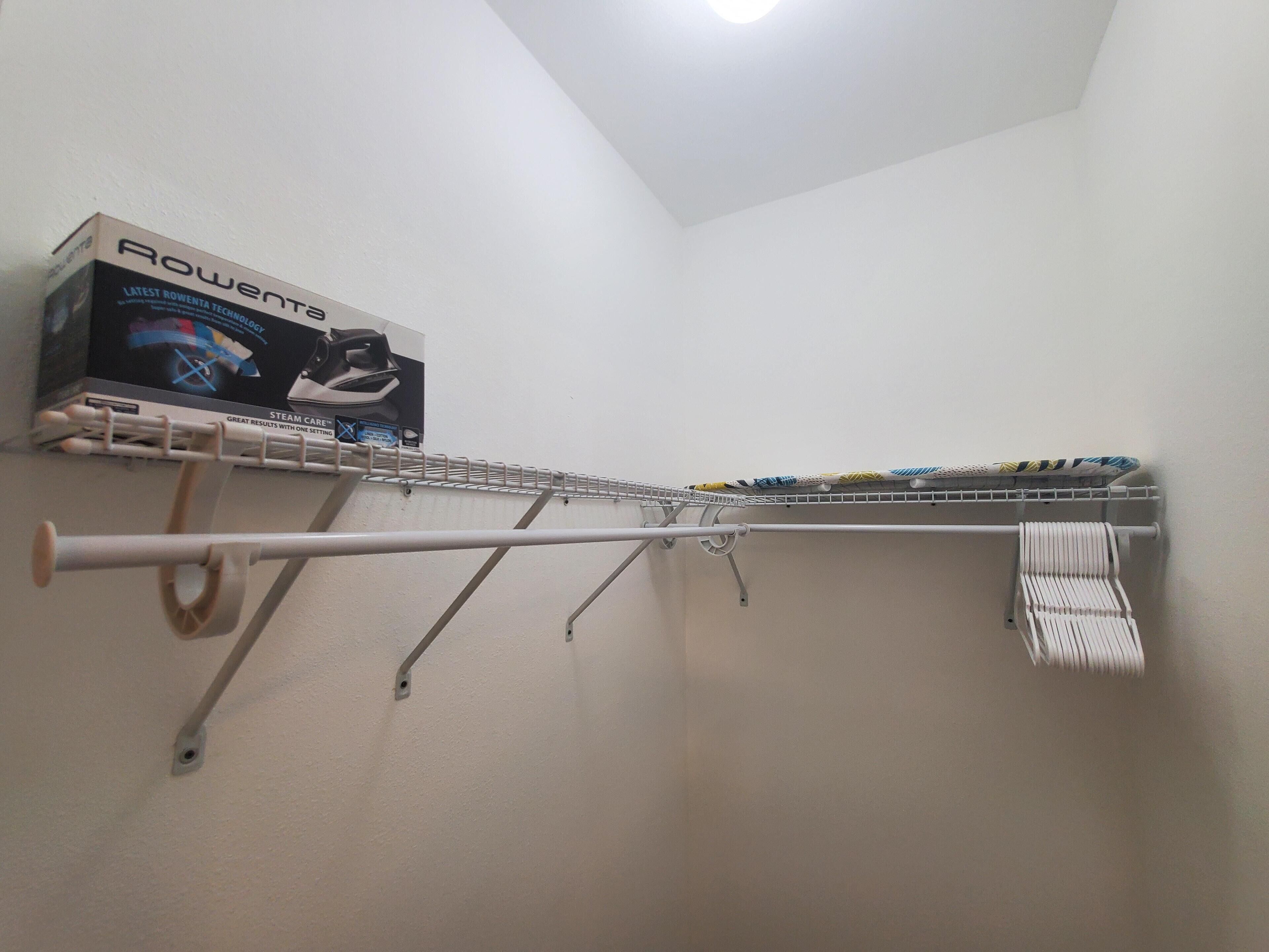 A laundry area with a wall-mounted rack holding various items, including a box labeled "Rowenta."