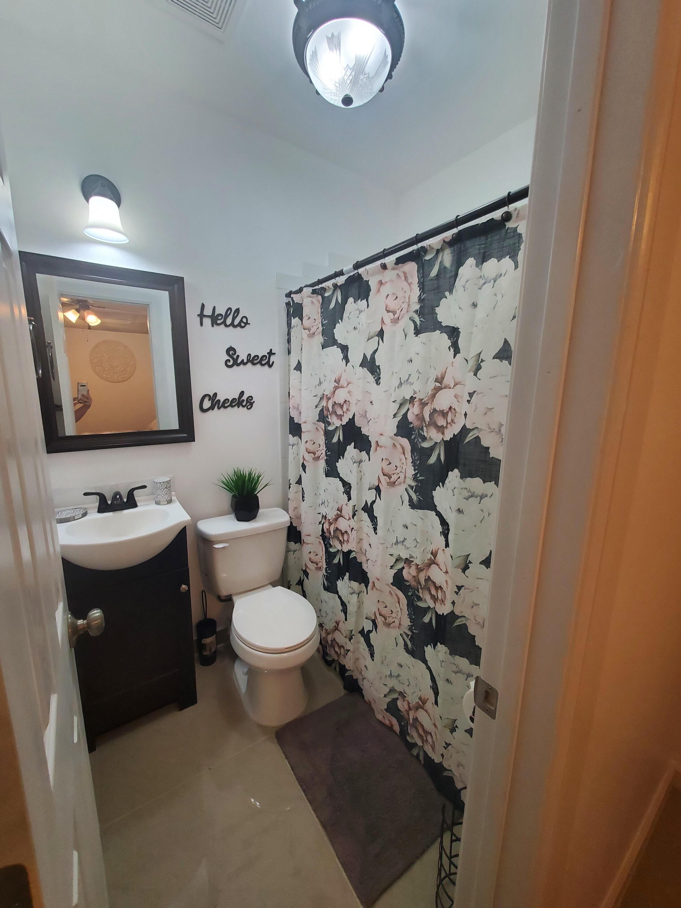 A bathroom with a toilet, sink, and a shower curtain with floral patterns.