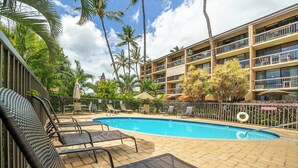 Un espace piscine d’hôtel avec des chaises longues et un bâtiment doté de balcons.