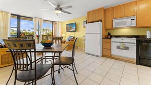 Une cuisine moderne avec des meubles en bois, un réfrigérateur blanc, un four à micro-ondes, une cuisinière et un ventilateur de plafond.
