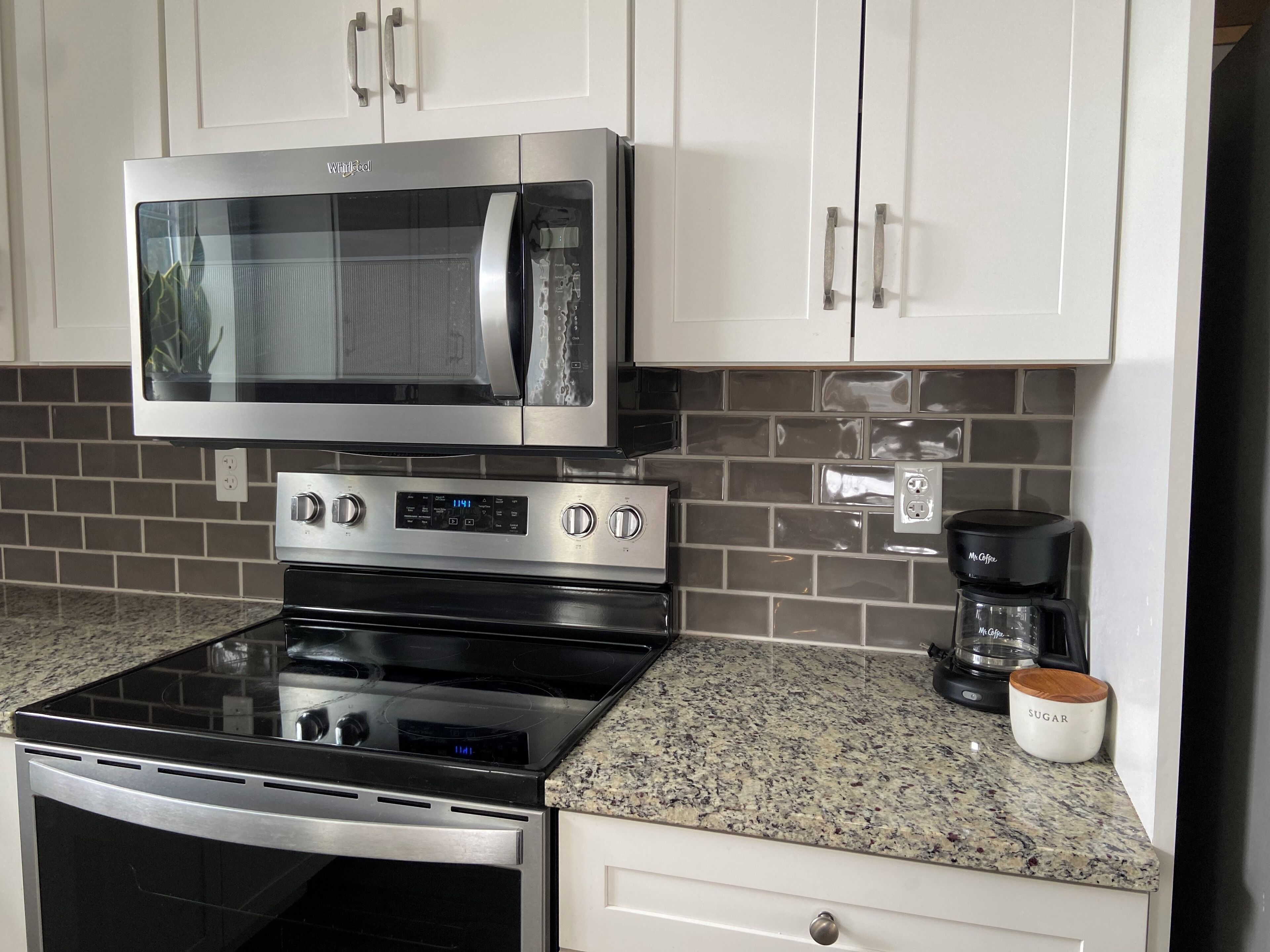 A kitchen with a microwave, stove, and coffee maker.