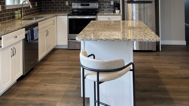A modern kitchen with white cabinets, granite countertops, stainless steel appliances, and a bar stool. - Newly Built Zen Space 2Bd-3Bth - Pets OK (Lititz)