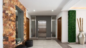 Eine moderne Lobby mit einer Steinwand, einem vertikalen Grünpflanzenwand und einem zentralen Aufzug.