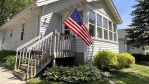A single-story house with a front porch, a small staircase, and a flag. - 3 Bed, 2 Bath Cozy Home Across from Zoo in the heart of Baraboo. (Baraboo)