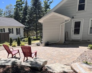 A patio with two red chairs and a stone feature. - 3 Bed, 2 Bath Cozy Home Across from Zoo in the heart of Baraboo. (Baraboo)