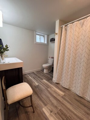 A bathroom with a shower curtain, a toilet, and a window above the toilet. - 3 Bed, 2 Bath Cozy Home Across from Zoo in the heart of Baraboo. (Baraboo)