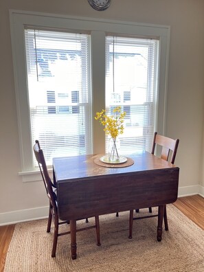 A dining table with chairs, a vase with yellow flowers, and a clock on the wall. - 3 Bed, 2 Bath Cozy Home Across from Zoo in the heart of Baraboo. (Baraboo)