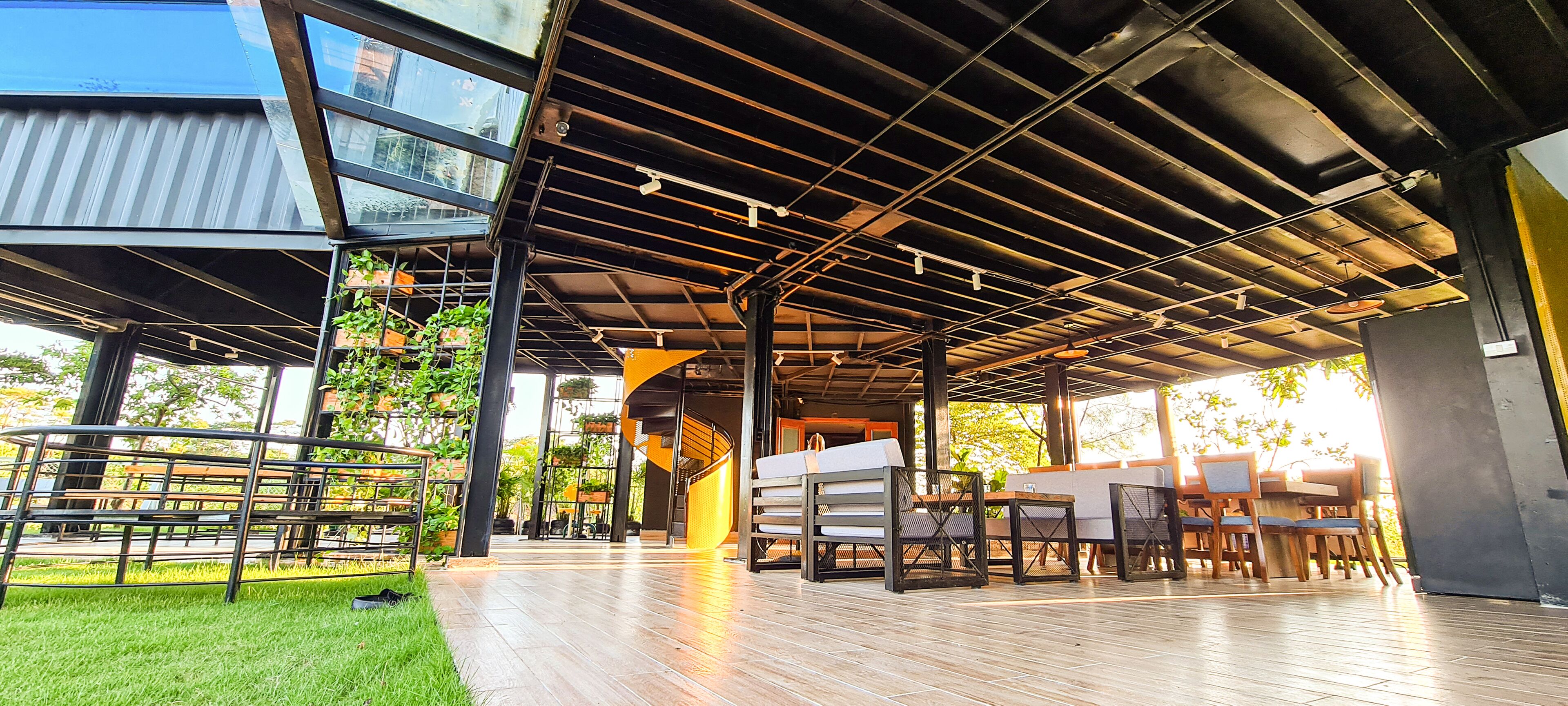 An outdoor patio area with a wooden deck, seating arrangements, and a staircase leading to an upper level.