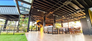 Un patio exterior con piso de madera, arreglos de asientos y una escalera que lleva a un nivel superior.