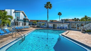 A swimming pool with blue tiles, surrounded by lounge chairs and palm trees. - Madeira Beach Yacht Club 215F by Distinctive Beach Rentals (Madeira Beach)