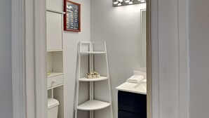 A bathroom with white shelves, a toilet, and a sink. - Madeira Beach Yacht Club 215F by Distinctive Beach Rentals (Madeira Beach)