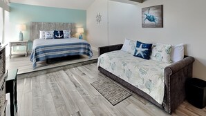 A bedroom with a bed, a sofa, a desk, and a ceiling fan. - Madeira Beach Yacht Club 215F by Distinctive Beach Rentals (Madeira Beach)