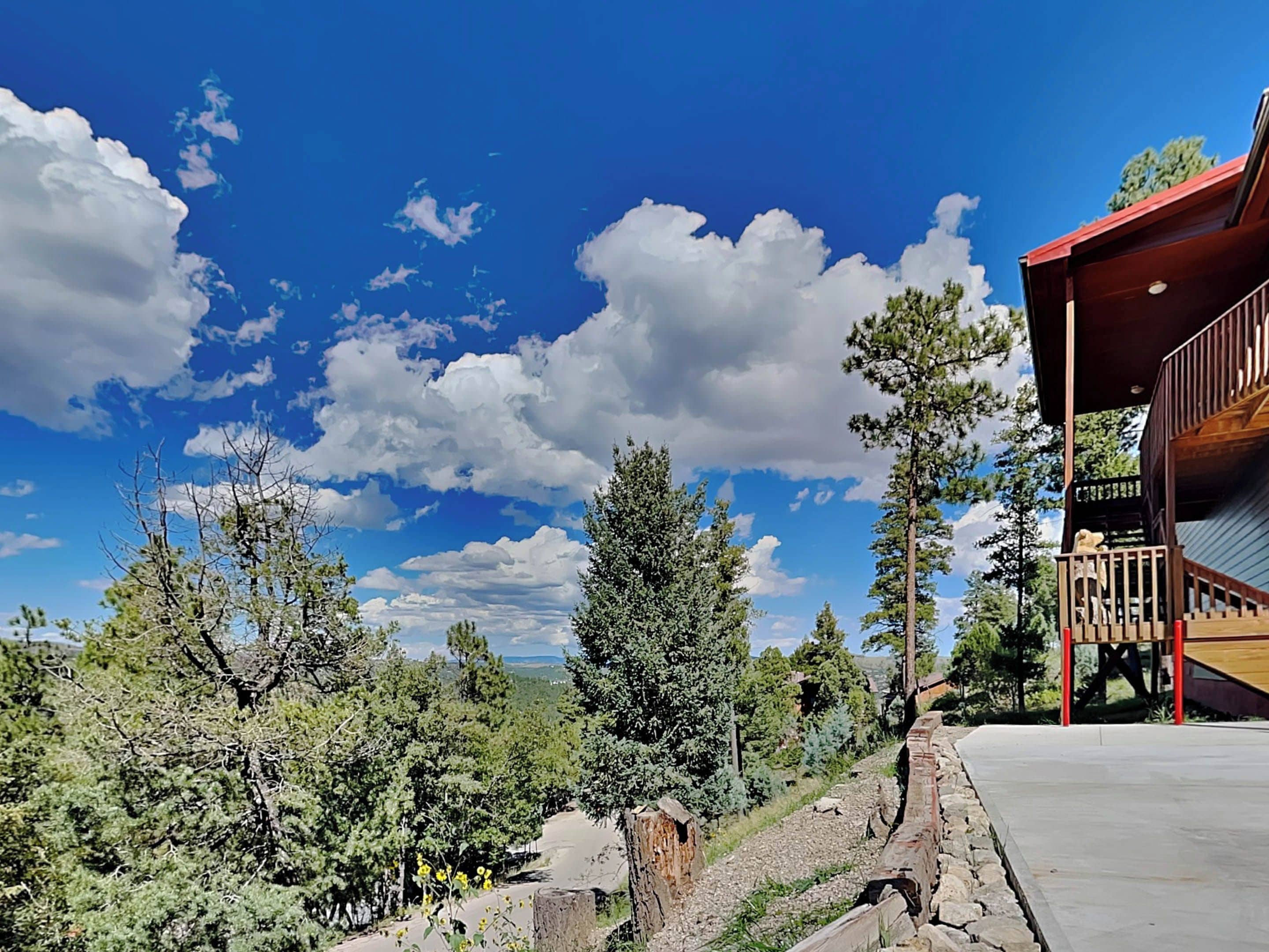 A wooden cabin with a balcony, surrounded by trees and a clear sky.