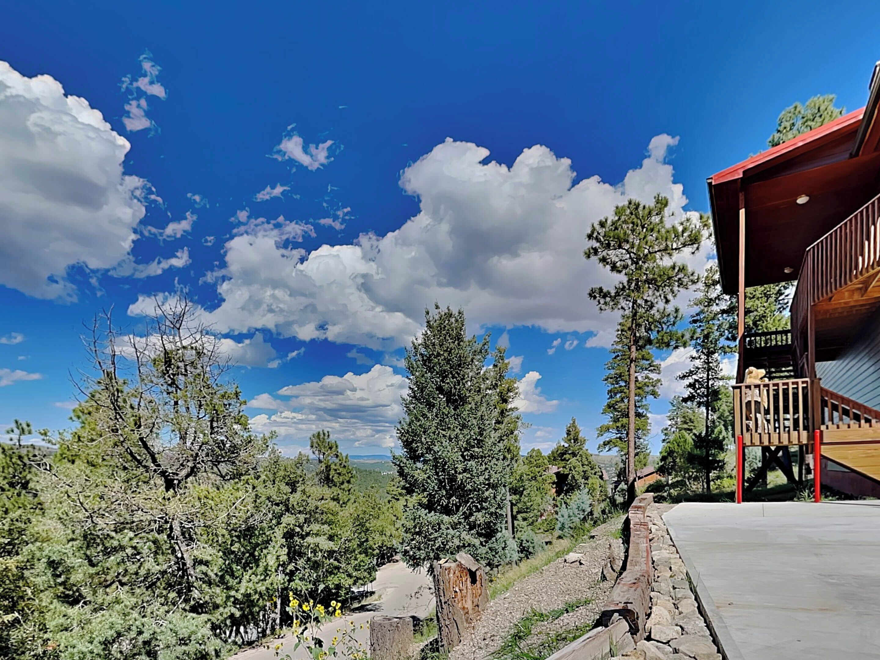 A wooden cabin with a balcony, surrounded by trees and a clear sky.