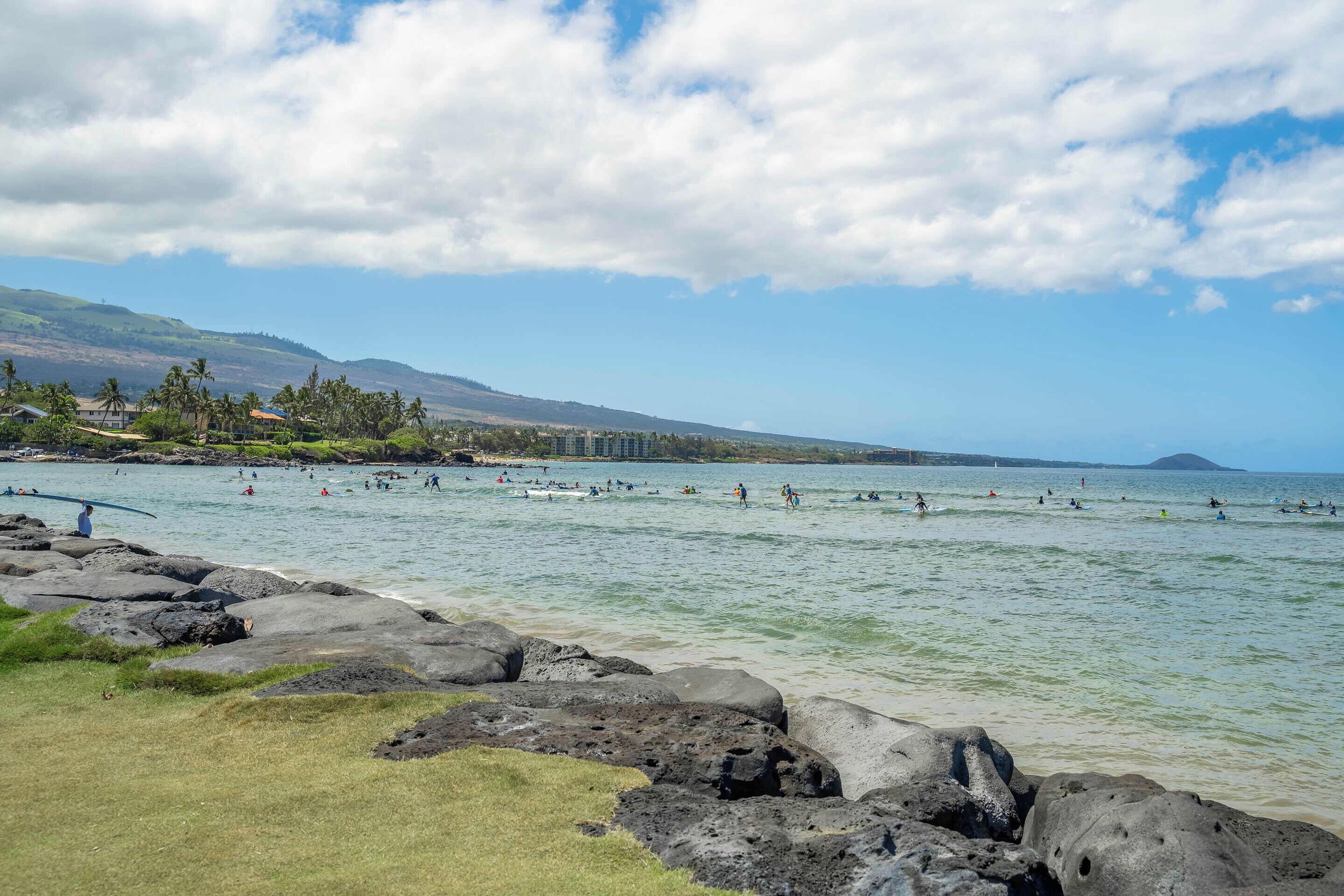A coastal area with rocky shores, clear water, and a distant mountain.