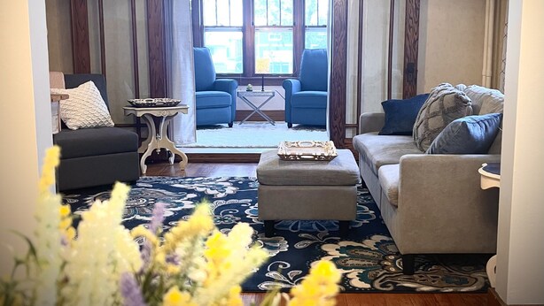 A living room with a ceiling fan, two armchairs, a sofa, a coffee table, and a patterned rug.