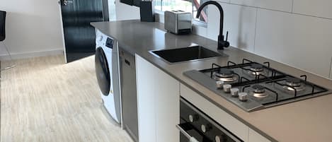 A modern kitchen with a stainless steel range hood, a built-in oven, and a dishwasher.