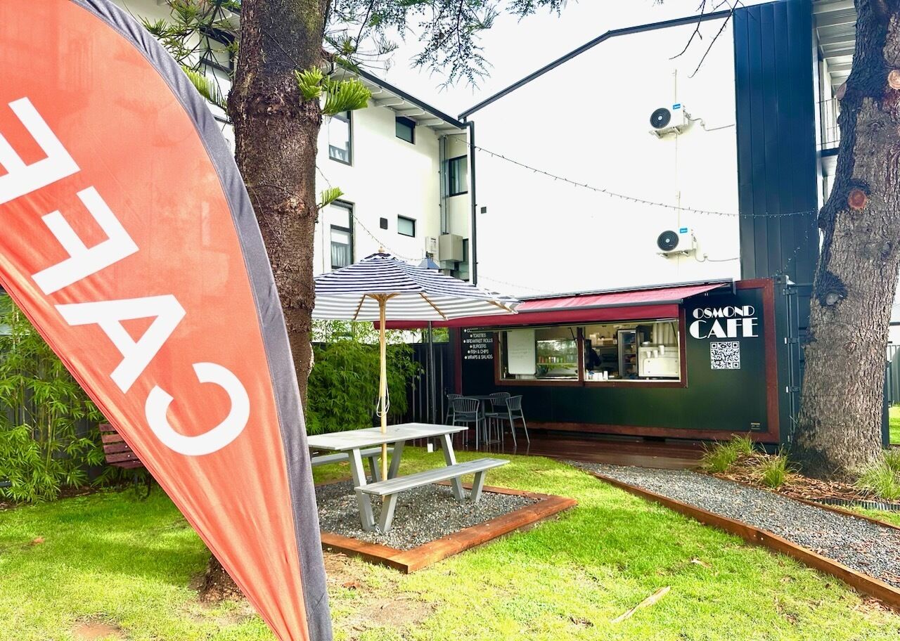 A café with outdoor seating, a picnic table, and a flag.