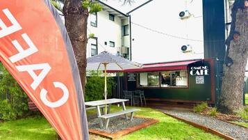 A café with outdoor seating, a picnic table, and a flag.