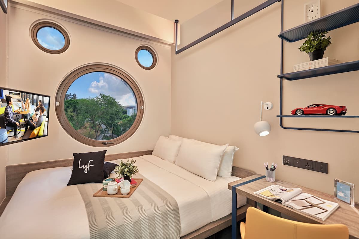 Ein modernes Hotelzimmer mit einem gro ßen Bett, einem kleinen Schreibtisch und einem Fenster mit Blick auf die Stadt.