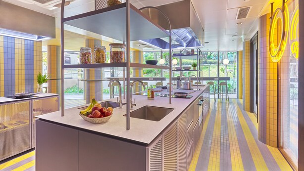 Une cuisine moderne dotée d’un îlot central, d’étagères intégrées et offrant une vue sur l’extérieur.