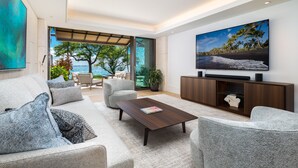 Een moderne woonkamer met een bank, fauteuils, een salontafel en een televisie.