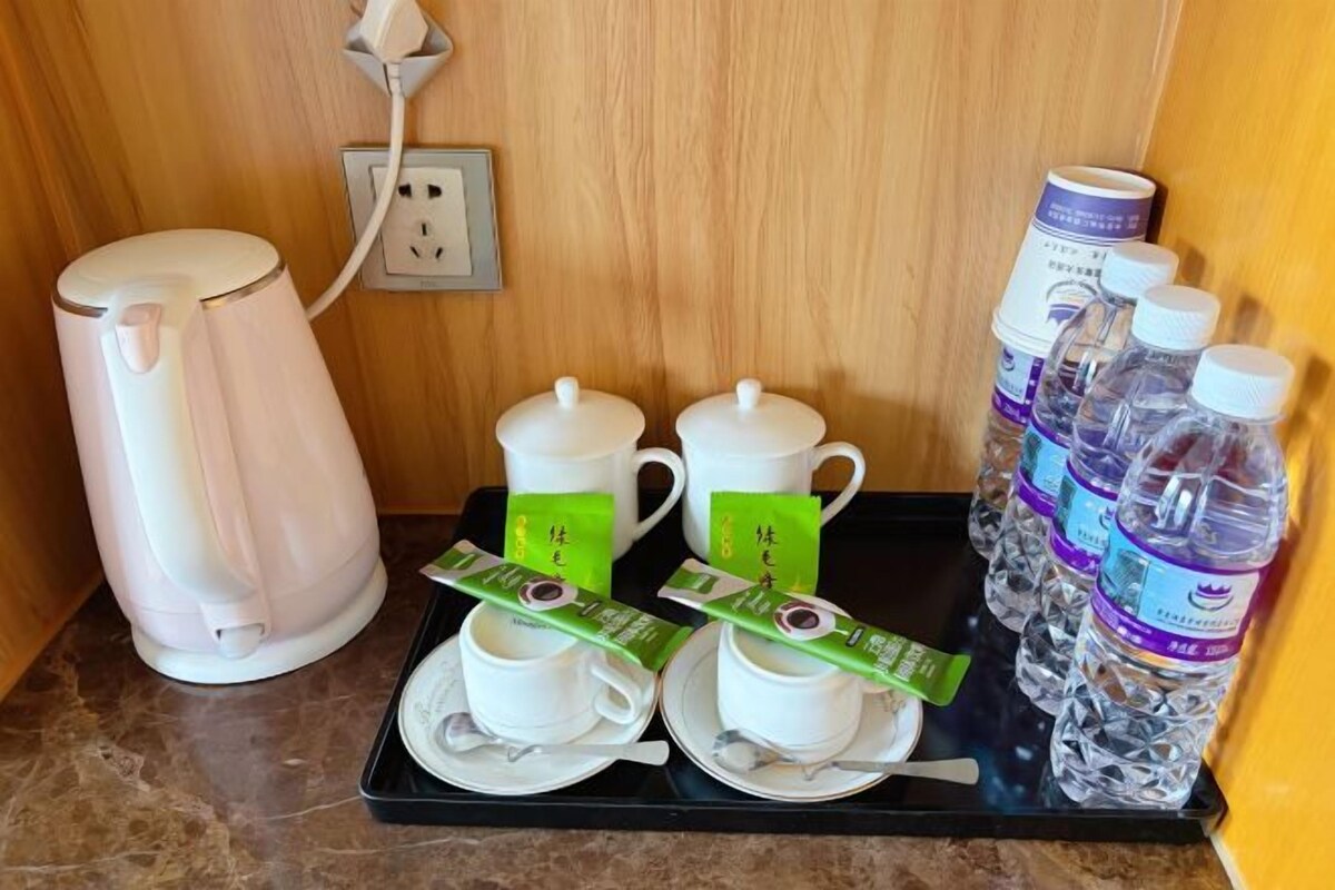A tray with a tea set, tea packets, and bottled water.