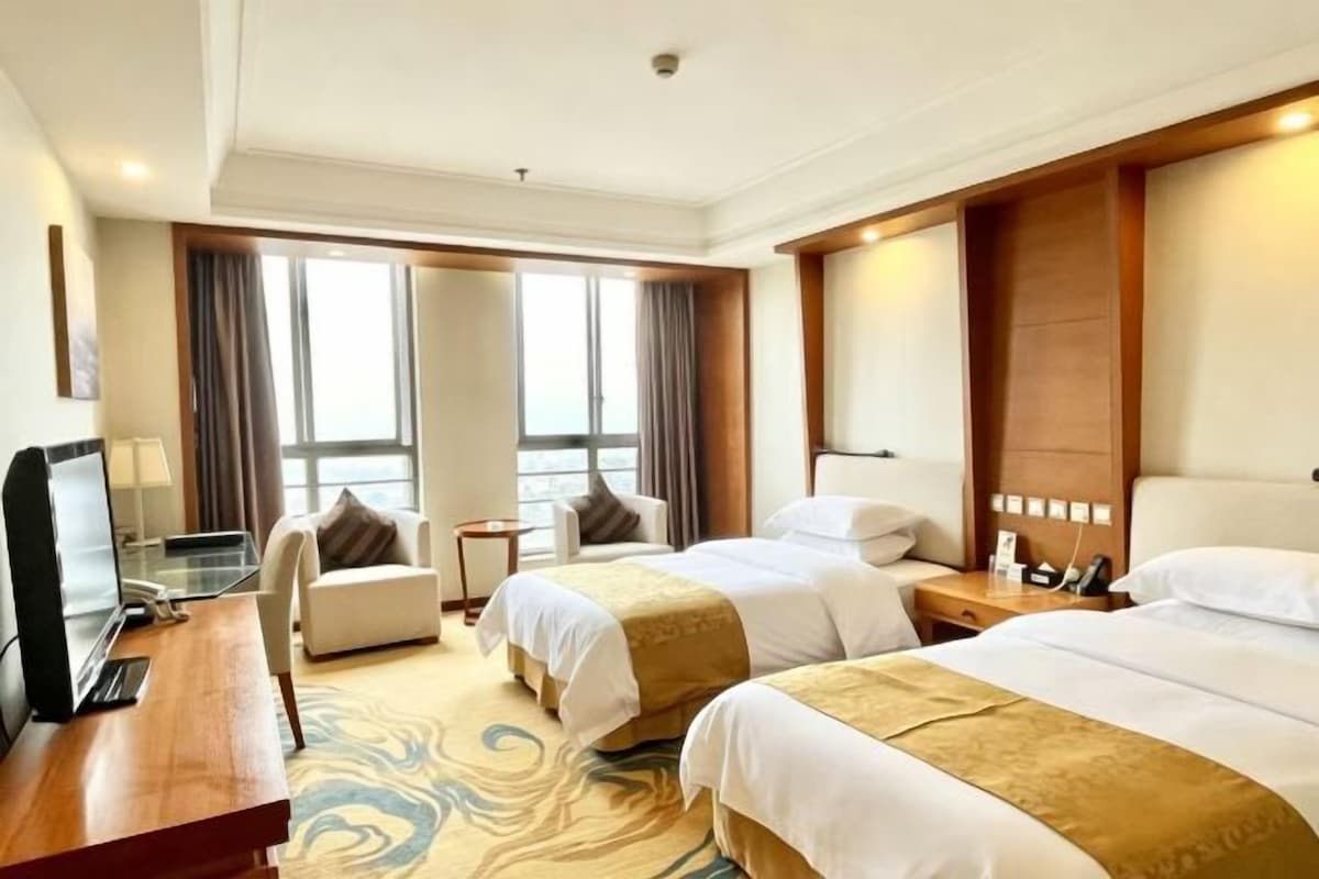 Une chambre d’hôtel avec deux lits, un bureau, une chaise et un téléviseur.