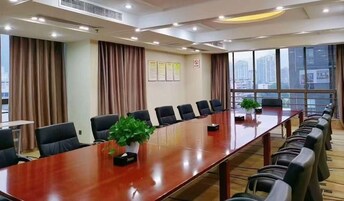 Un salón de conferencias con una mesa larga, sillas y una planta en maceta.