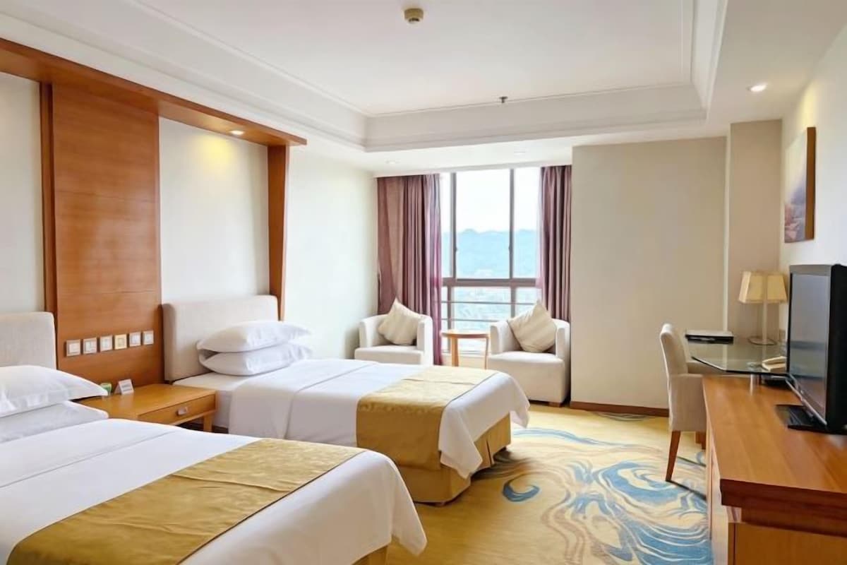 Une chambre d’hôtel avec deux lits, un bureau, une télévision et une vue sur la mer.