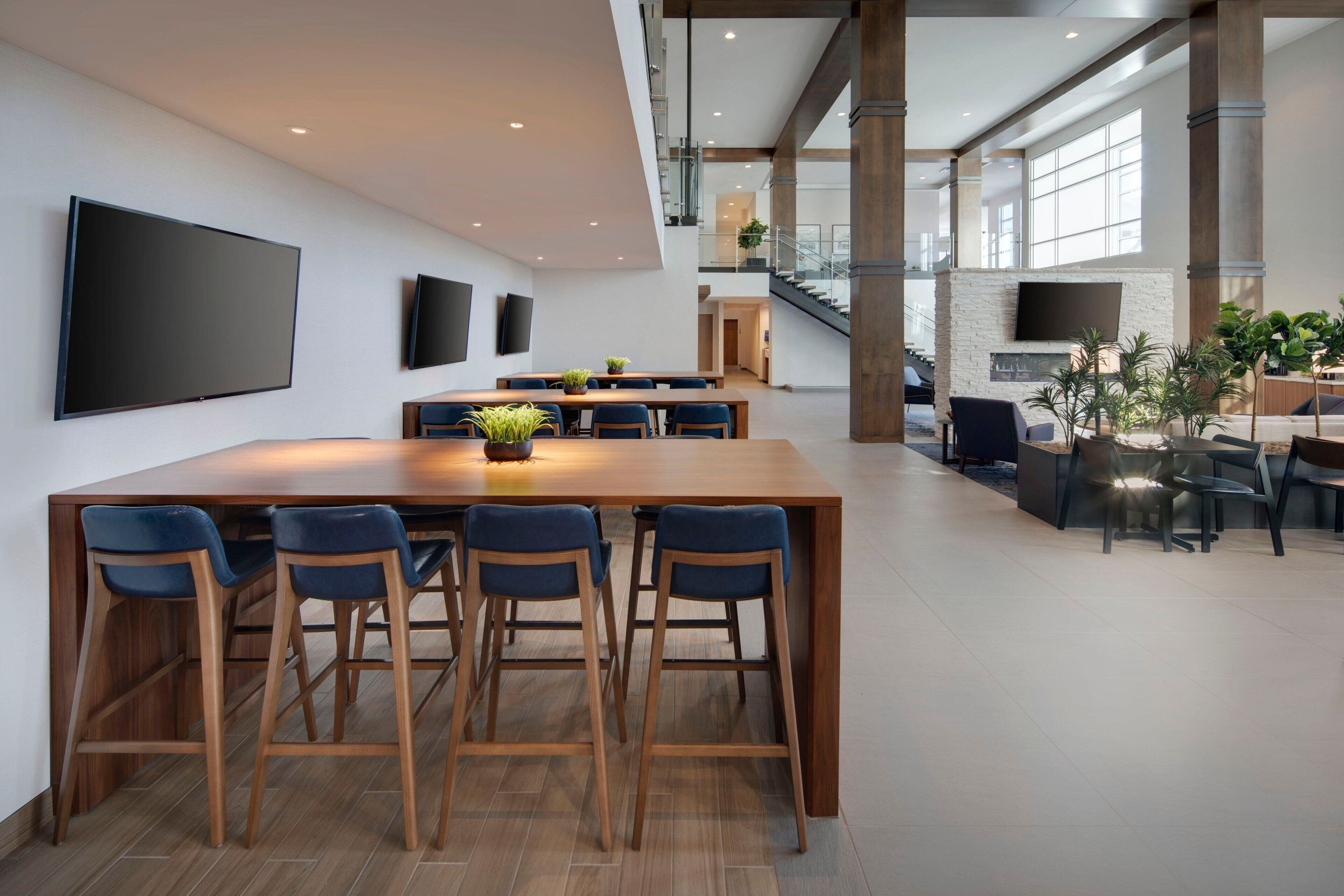 A spacious, modern kitchen with a large island, bar stools, and a flat-screen TV mounted on the wall.