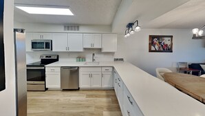 A modern kitchen with white cabinets, a built-in oven, and a dishwasher. - Hibiscus 301-A by Distinctive Beach Rentals (St. Augustine)